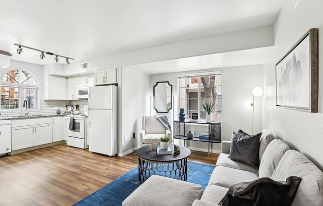 A modern living room with a grey sofa and a kitchen area in the background.