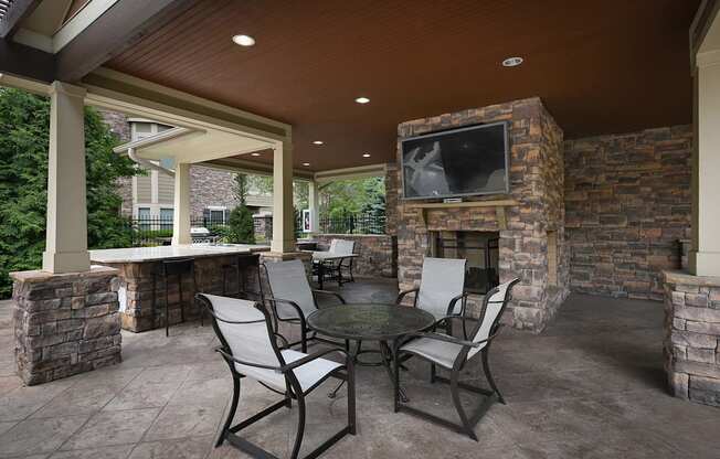 a covered patio with a table and chairs and a fireplace at Sovereign at Overland Park, Kansas  