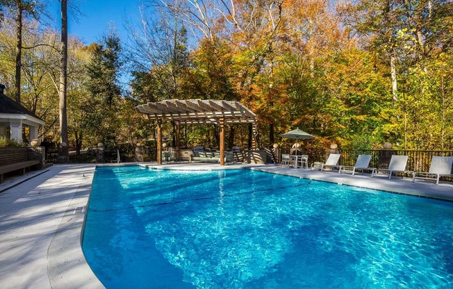 a swimming pool with a pergola and chairs