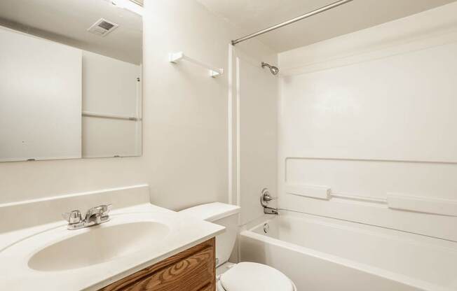 A white bathroom with a sink, toilet, and bathtub.
