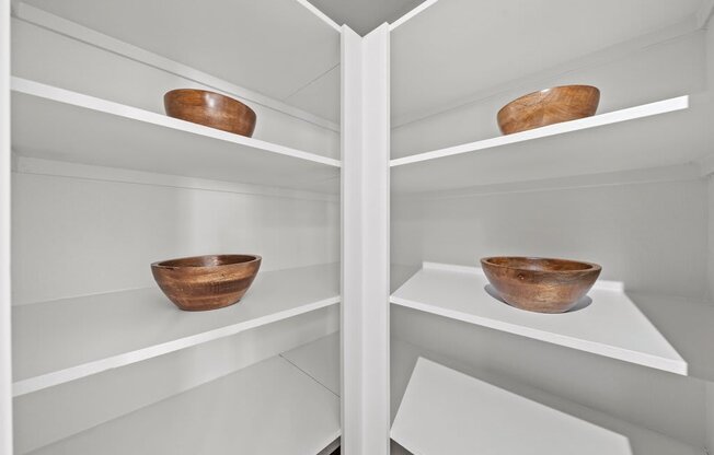 Two wooden bowls on shelves in a white refrigerator.