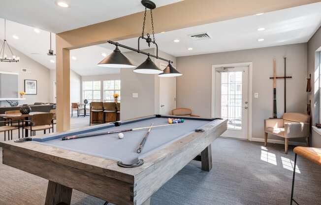 a pool table in the clubhouse of a home with a living room and dining area