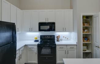 a white kitchen with black appliances and white cabinets