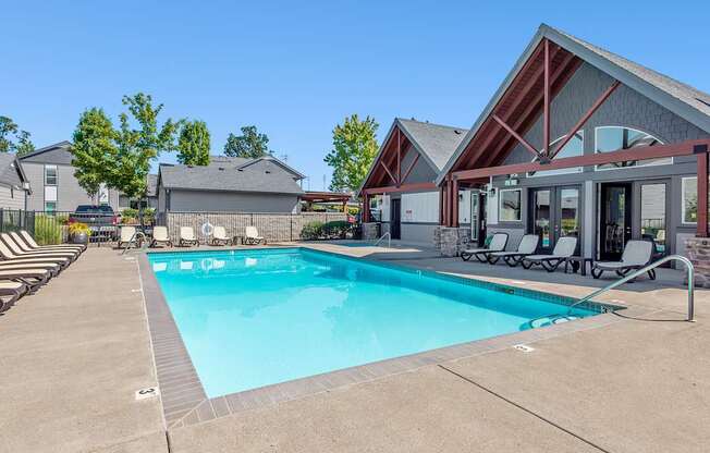 A swimming pool with a clubhouse in the background at The Landing Apartments and Townhomes, Oregon, 97045
