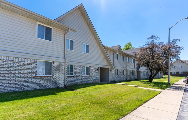 a row of houses with a sidewalk and green grass