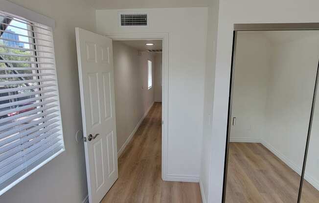 Bedroom with mirrored closet doors and lots of natural light in one bedroom apartment at the Atrium Apartments in San Diego, CA.