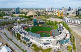 A large stadium with a green field in the center and a yellow structure in the background.