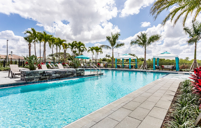 exterior pool with patio furniture and palm trees on sunny day