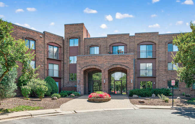 A red brick building with a large arched entrance and a small garden in front.
