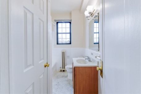 bathroom with vanity, tub, toilet, large mirror and window at the dahlia apartments in Washington dc