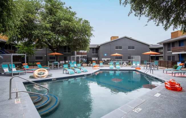 Large community pool at Stadium 700 apartments in Arlington, TX with lounge chairs and inflatable pool rings