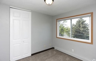 a bedroom with a large window and a white door at Southern Manor Apartments, Grand Forks, ND