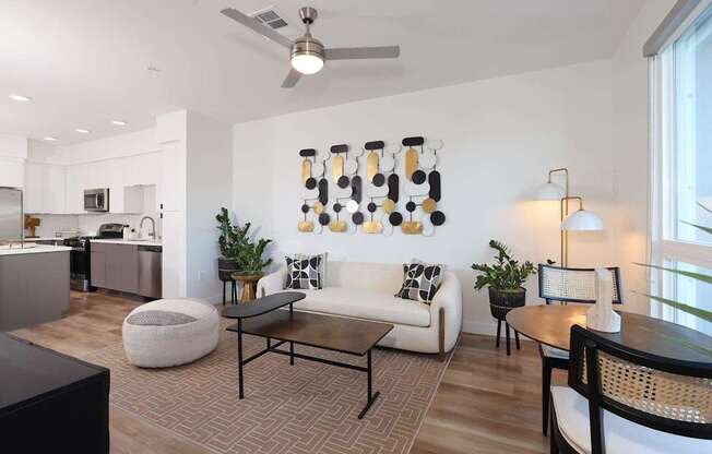 A modern living room with a white couch, a coffee table, and a ceiling fan.