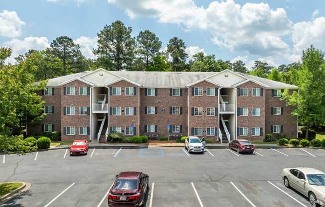 an empty parking lot with cars in front of an apartment building