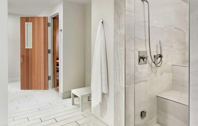 A white tiled bathroom with a wooden door and a white bench.