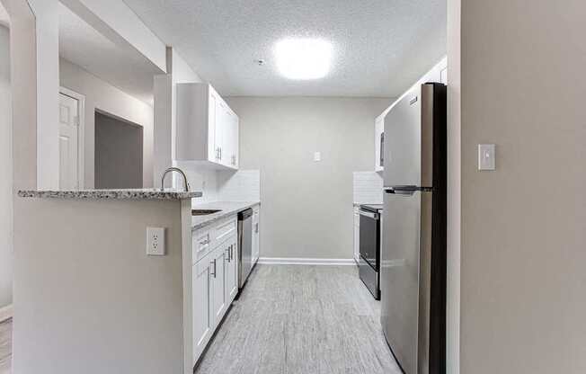 A kitchen with a refrigerator, cabinets, and a counter.
