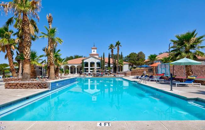 a swimming pool with palm trees and a building in the background