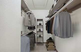 a spacious closet with clothes hanging on a rack and a shelf