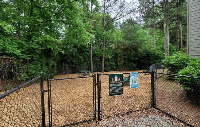 A fenced area with signs and trees in the background.