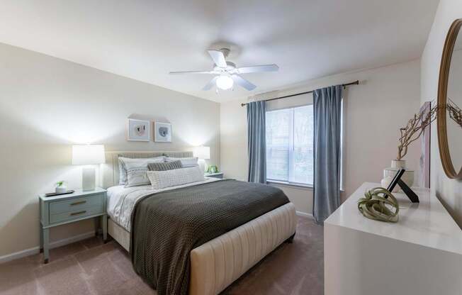 A bedroom with a bed, nightstand, and a mirror on the wall.