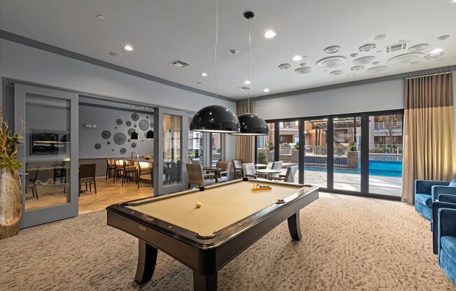a pool table in a living room next to a swimming pool
