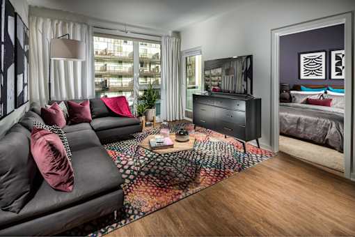 A living room with a black couch and a wooden floor.