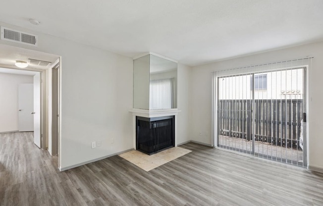 an empty living room with a fireplace and a door to a balcony