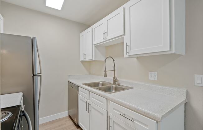 Kitchen with white cabinets and a sink and a refrigerator at Verde Apartments in Tucson.