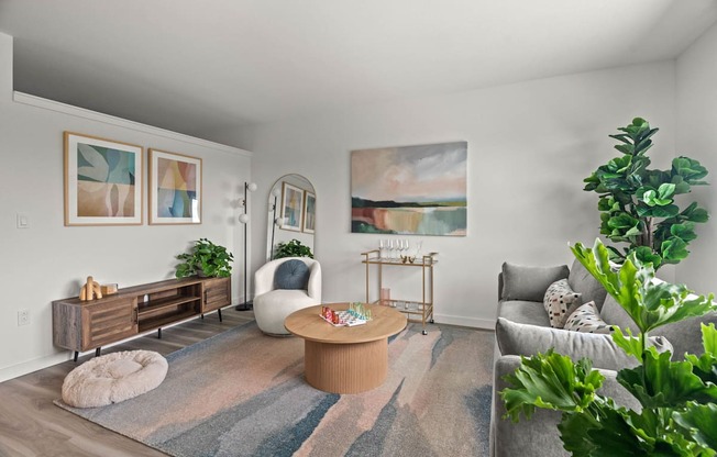 A living room with a grey couch, a white chair, a wooden coffee table, and a painting on the wall.