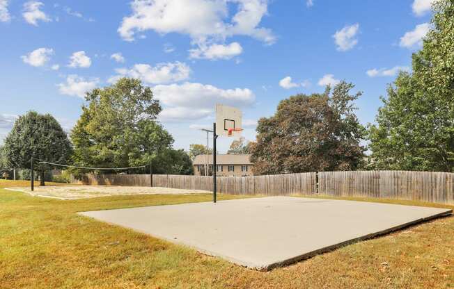 a basketball court in a backyard with a fence and trees