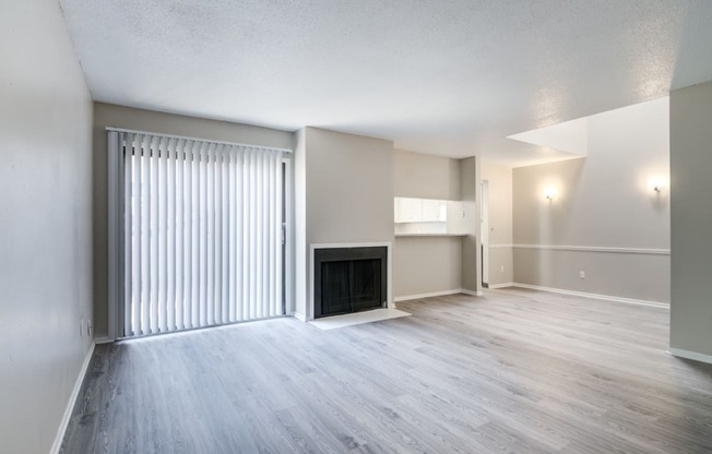 an empty living room with a fireplace and sliding glass doors