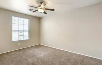 Generously sized bedroom adorned with plush carpeting and equipped with a soothing ceiling fan to enhance your comfort