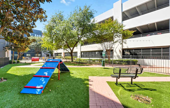 A playground with a blue slide and a bench in front of a building.
