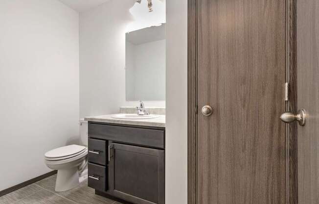 A bathroom with a toilet, sink, and mirror.