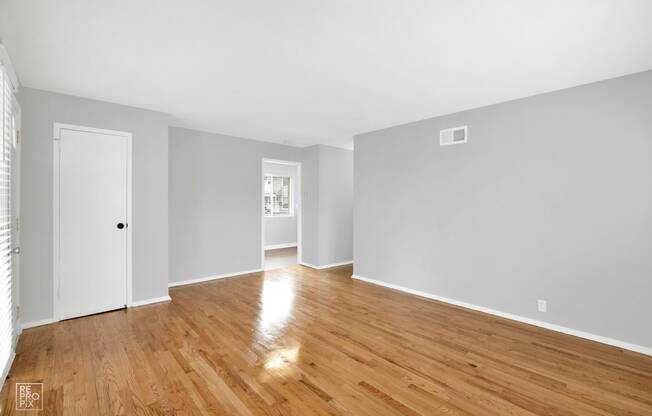 a bedroom with grey walls and a hardwood floor