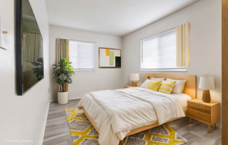 A bedroom with a bed, nightstand, and a plant.