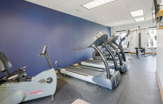 24-hour fitness center with a row of treadmills and other exercise equipment