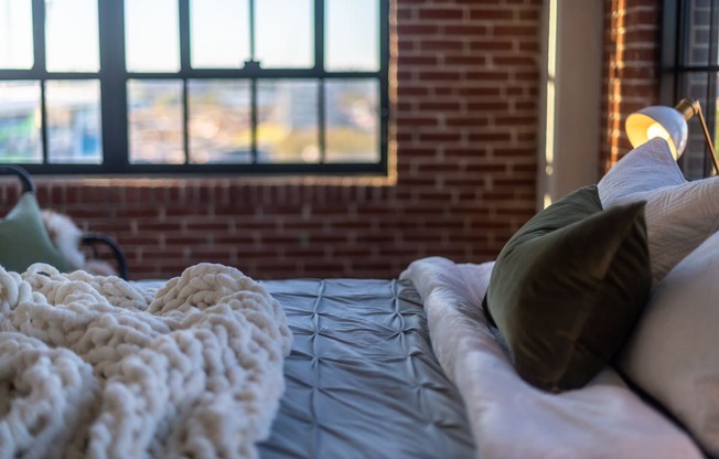 a bed with a blanket and pillows in front of a window at The 22 Apartments, Missouri, 63103