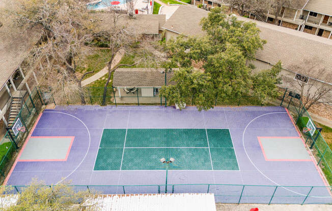 an aerial view of a tennis court and a house on a blue and green court