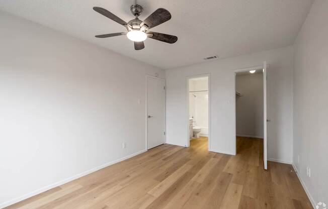 A room with a ceiling fan and wooden floors.