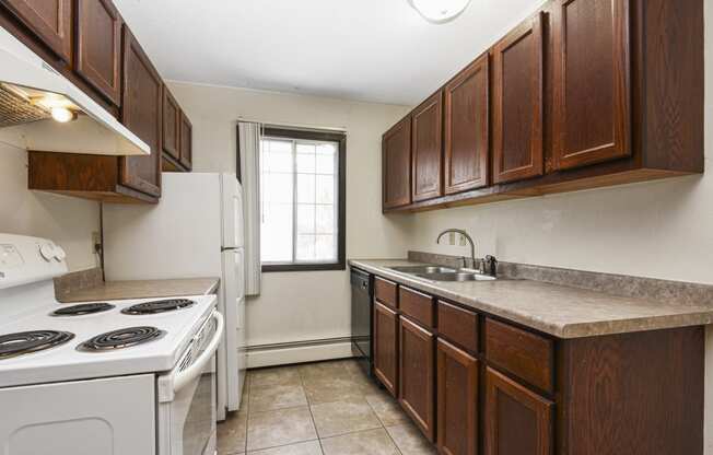 Fridley, MN Georgetown Apartments. A kitchen with brown cabinets and white appliances