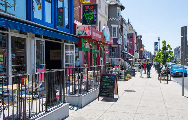 A street view of a shopping area with a signboard in the foreground.
