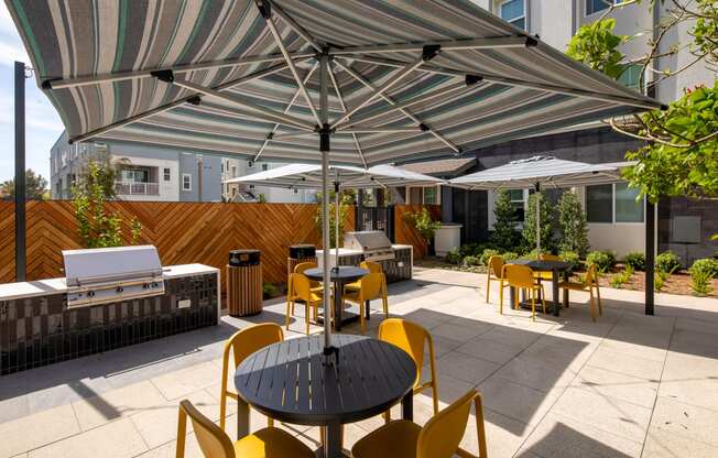 A patio with a table and chairs under a striped umbrella.