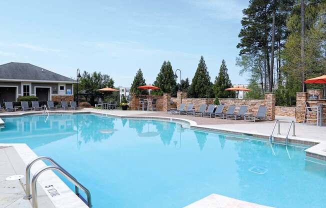 A large swimming pool with a metal ladder and a small building in the background.