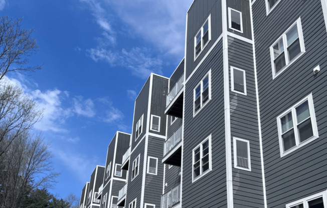 a gray apartment building with white windows against a blue sky