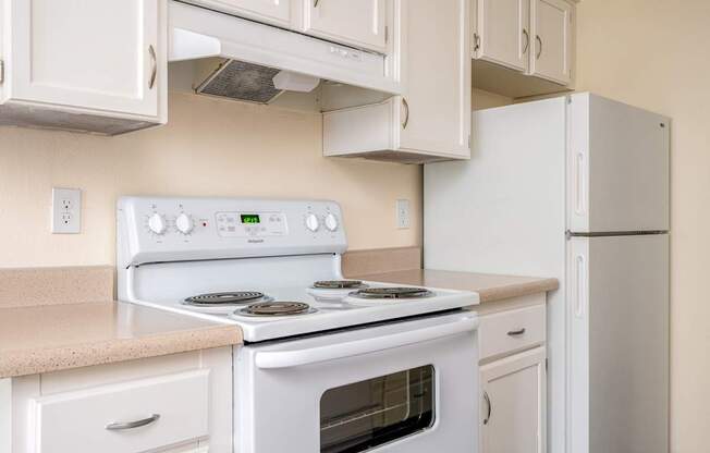 A white stove top oven with a white refrigerator in a kitchen.