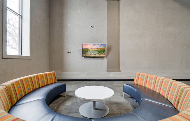 circular couch facing TV on a wall