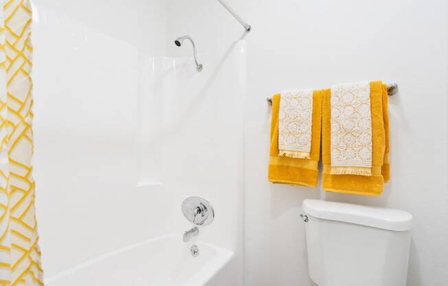 a bathroom with two yellow towels and a white shower