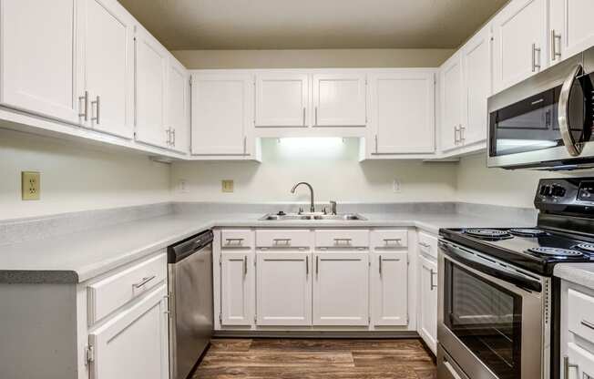 kitchen with white cabinetry, stainless appliances, and hardwood-style flooring