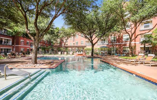 A swimming pool surrounded by trees and chairs.